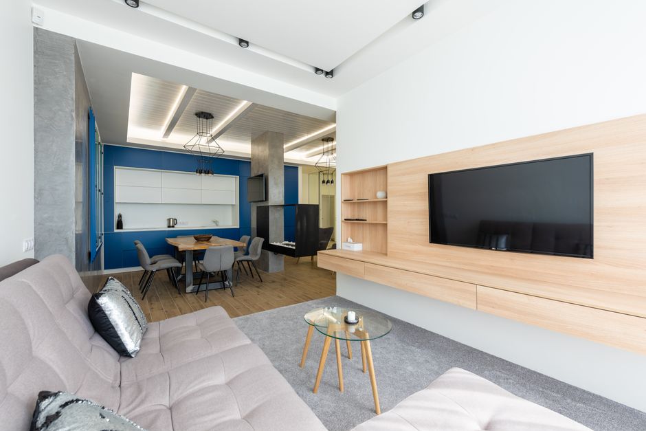Sala de estar moderna com espaço de convivência e integração visual entre a área de lazer e a cozinha, com decoração minimalista e acabamento clean.