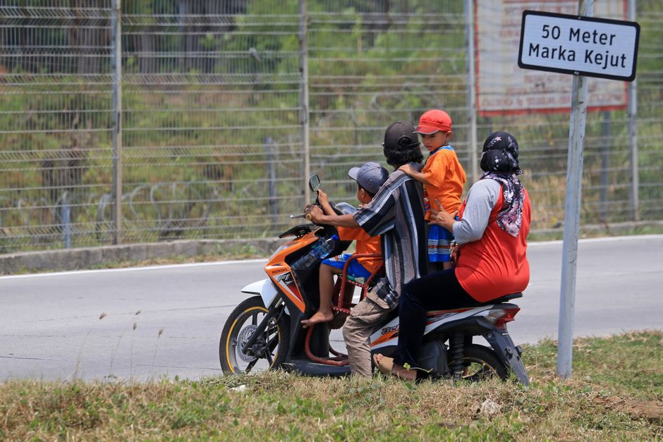 Família divertida viajando de moto na estrada, destacando o tema de transporte e momentos familiares ao ar livre.