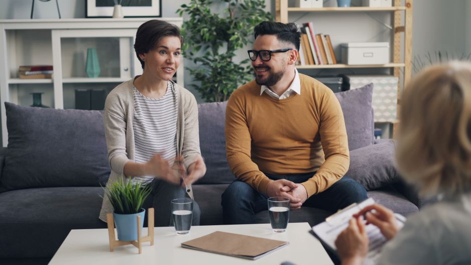 Dupla participando de uma sessão de aconselhamento ou terapia em um ambiente acolhedor e confortável.