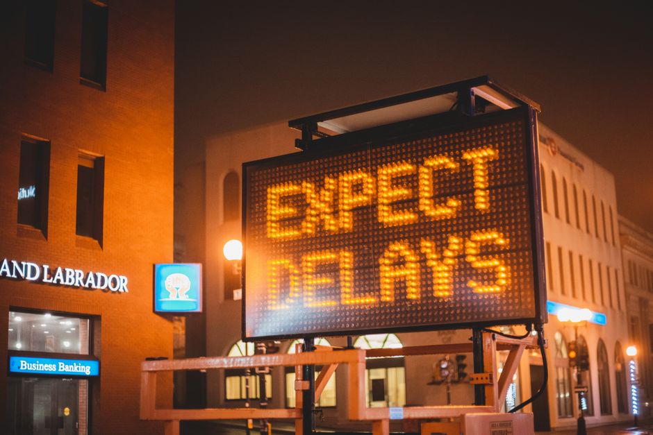 Painel digital com mensagem de advertência sobre atraso nas expectativas, em ambiente urbano à noite.