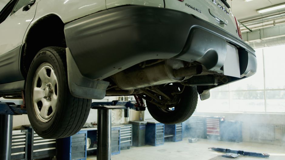 Imagem de um carro elevado em um centro de manutenção, indicando inspeção ou reparo técnico.