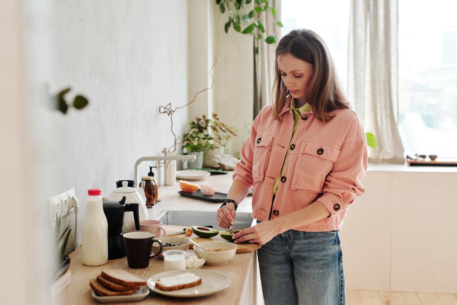 Mulher preparando café da manhã no estilo minimalista com luz natural e ambiente acolhedor.