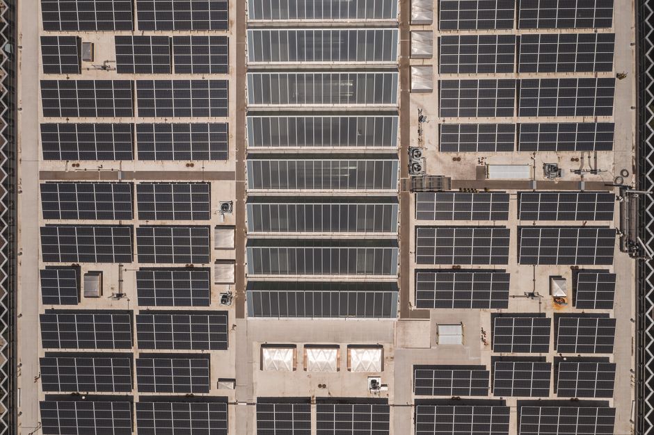 Visão aérea de uma instalação de painéis solares em um prédio comercial, destacando o uso de energia renovável no ambiente corporativo.
