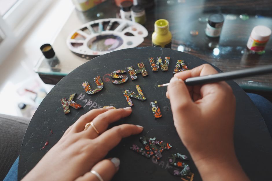 Pessoa decorando letras coloridas em uma placa de vidro para comemoração ou evento especial.