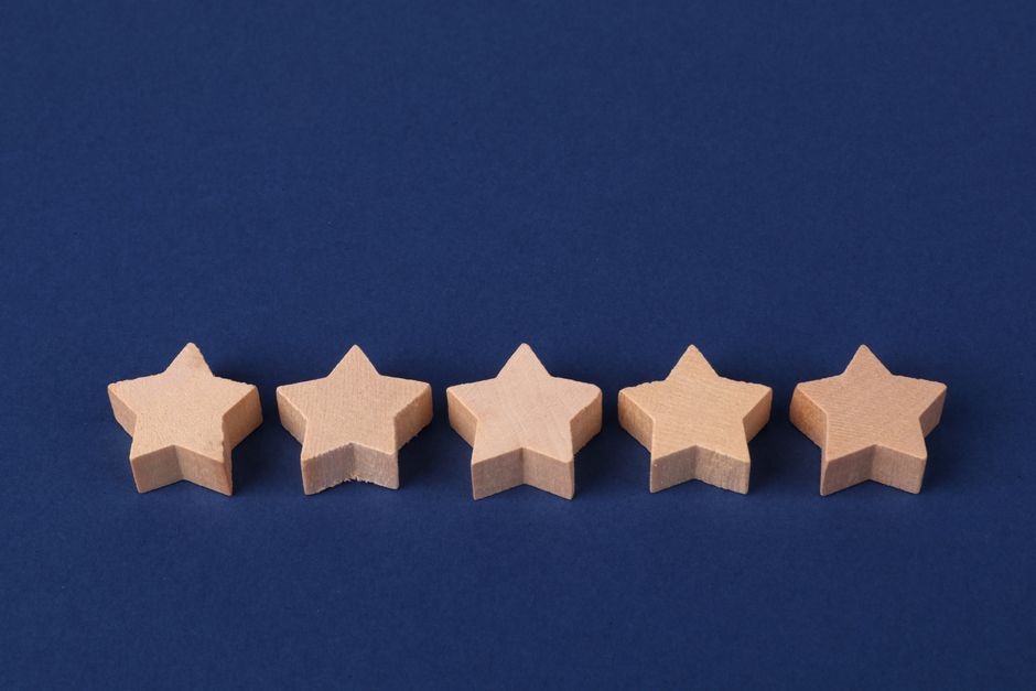 Estrelas de madeira alinhadas sobre fundo azul representando avaliação ou satisfação em um contexto de qualidade ou desempenho.