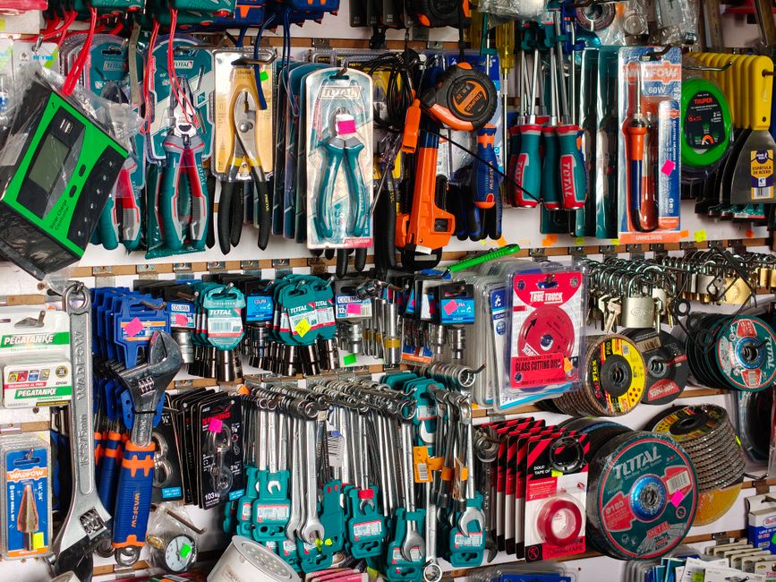 Imagem de uma loja de ferramentas com uma variedade de produtos organizados em prateleiras, incluindo brocas, serrotes, alicates e demais utensílios manuais e elétricos.