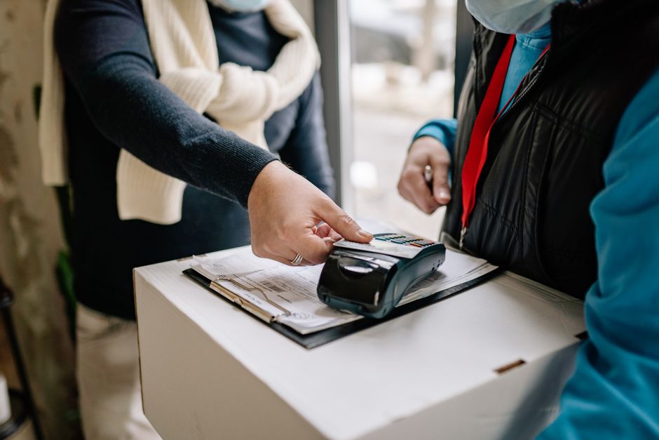 Pessoa realizando pagamento com cartão de crédito em um ambiente de atendimento ao cliente, com foco em transações financeiras e assistência ao consumidor.