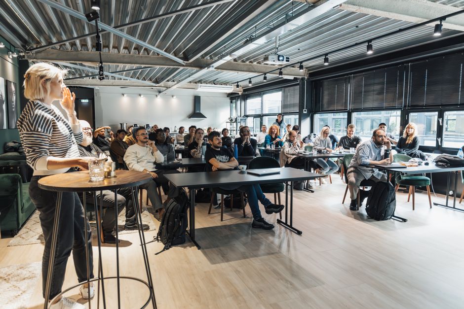 Mulheres conduzindo uma palestra ou workshop para um público diversificado em ambiente corporativo moderno
