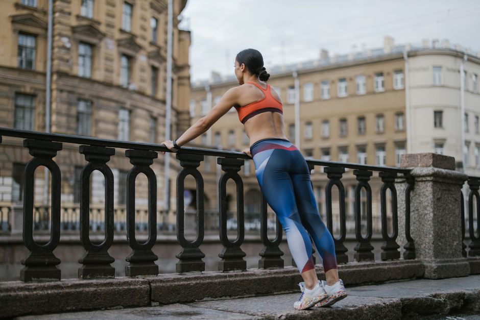 Mulher praticando exercícios ao ar livre em ambiente urbano, focada em bem-estar e saúde física.