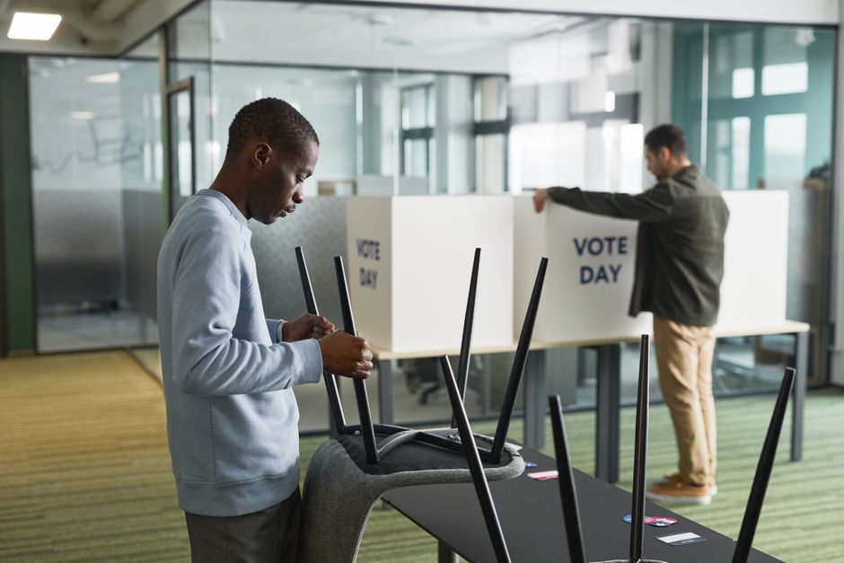Jovem eleitor se preparando para votar em uma cabine de votação no dia de eleições, evidenciando o processo democrático de voto.