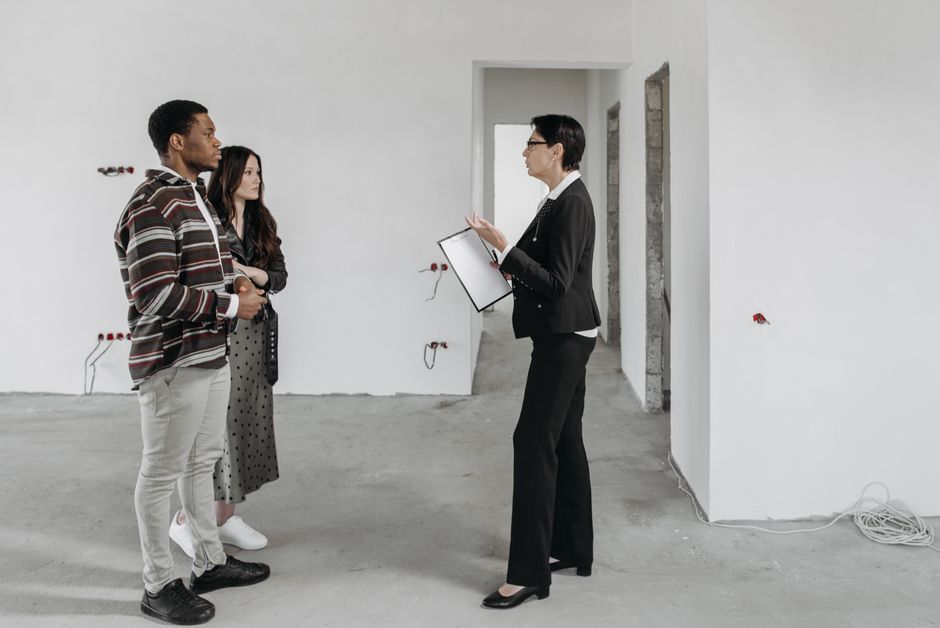 Três pessoas conversando em uma obra ou construção, representando planejamento ou avaliação de projetos.