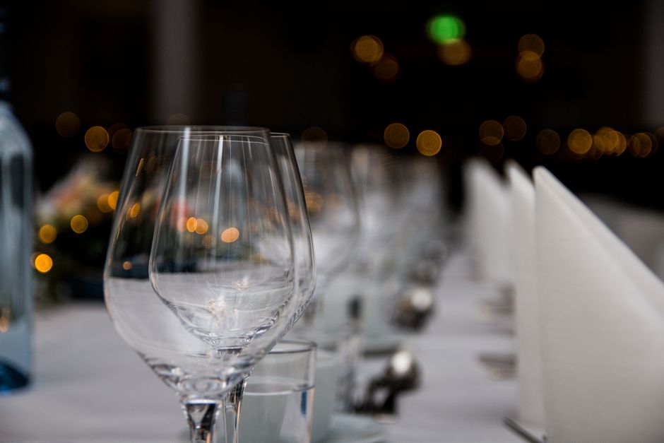 Imagem de uma mesa de jantar elegantemente preparada, com taças de vidro e toalha branca, ideal para um blog sobre eventos sociais ou gastronomia sofisticada.