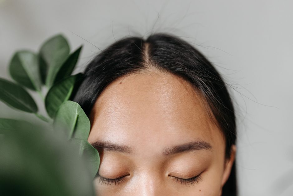 Retrato de uma mulher com os olhos fechados, cercada por plantas, transmitindo tranquilidade e conexão com a natureza.