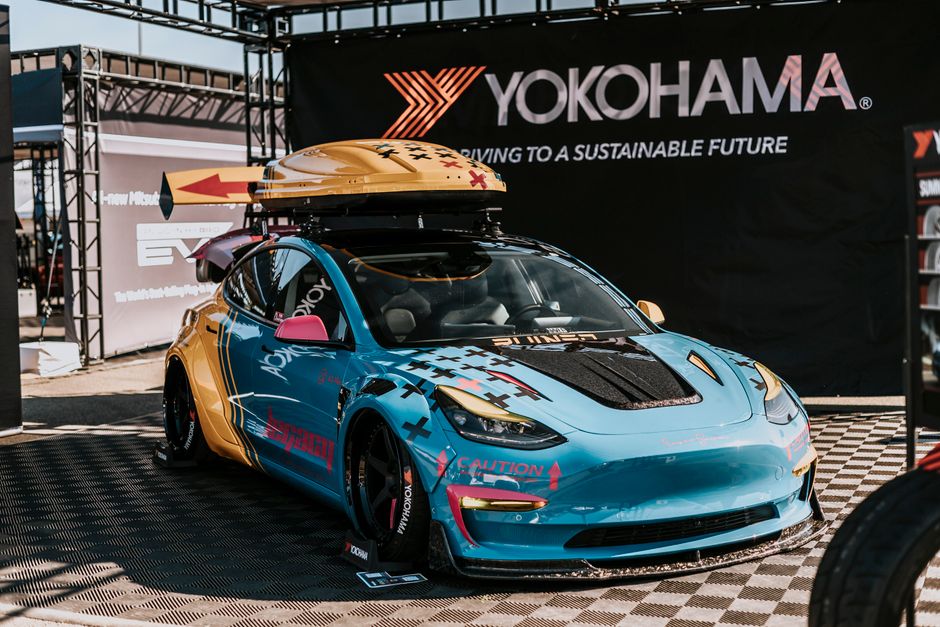 Carro de corrida com equipamento para aventura sustentável exibido em evento da Yokohama, destacando inovação e esportes motorizados.