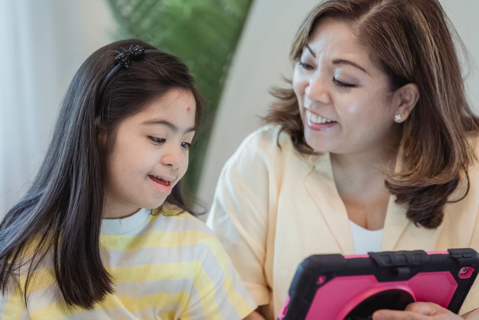Mulher e criança interagindo com um dispositivo eletrônico, mostrando conexão familiar e tecnologia educativa.