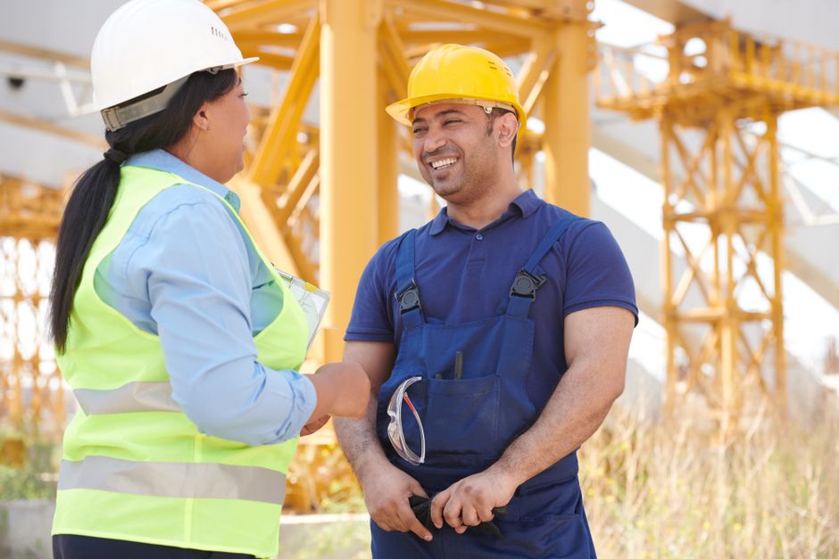 Duas pessoas no canteiro de obras trocando um aperto de mão, simbolizando parceria e colaboração na construção civil.