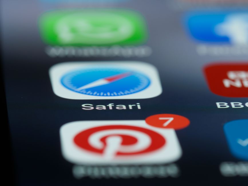 Imagem de tela de smartphone com ícones de aplicativos, incluindo o browser Safari e o Pinterest, em foco, representando uso de dispositivos móveis para navegação e pesquisa online.