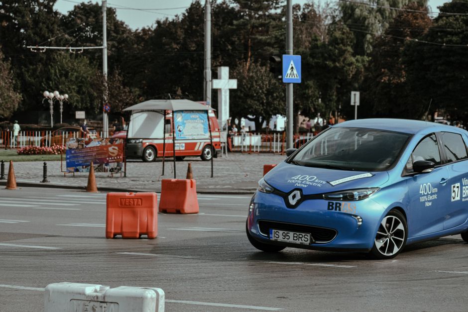 Carro elétrico de alta performance em trecho de rua urbana, com elementos de sinalização e infraestrutura de transporte sustentável.
