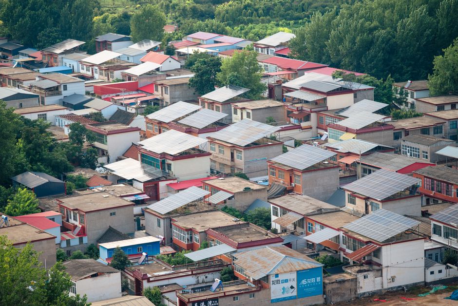 Imagem aérea de uma comunidade residencial com telhados em painéis solares, destacando o tema de sustentabilidade e energia renovável em áreas urbanas.