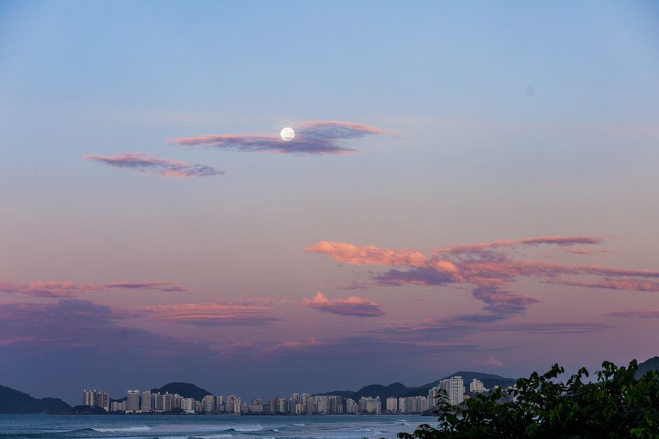 Paisagem noturna com a lua sobre o mar, destacando uma cena tranquila e natural ao entardecer ou início da noite.