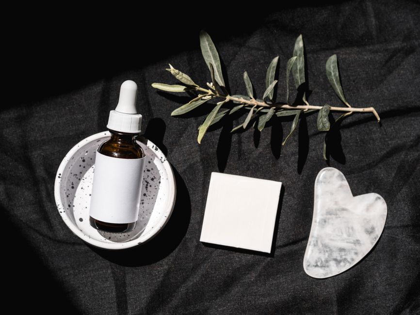 Imagem minimalista com produtos de beleza e bem-estar dispostos sobre um fundo preto, transmitindo uma atmosfera de cuidado pessoal e spa.