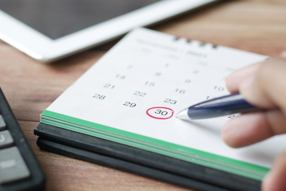 Pessoa marcando a data final de um plano ou rotina importante em um calendário, simbolizando gestão de tempo ou metas.