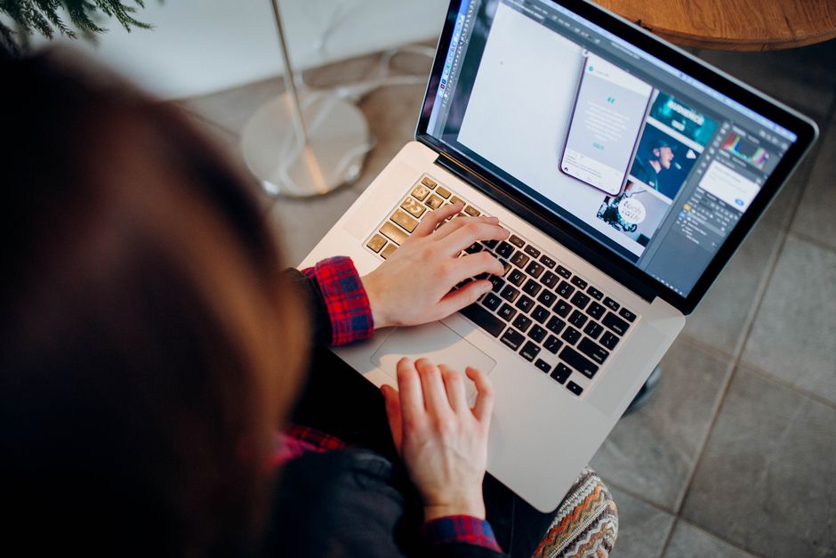 Pessoa trabalhando na criação de conteúdo digital ou design gráfico usando um laptop com foco em aplicativos de edição de imagem ou design.