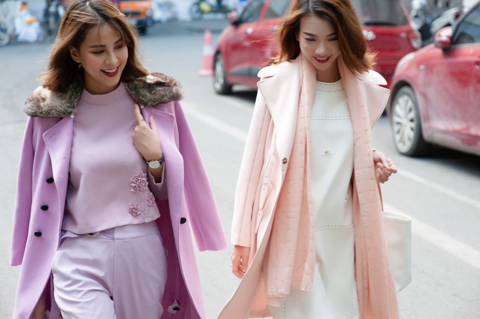 Duas mulheres sorridentes caminhando descontraidamente na rua, vestindo roupas elegantes e bem coordenadas, transmitindo uma sensação de alegria e estilo em um dia comum.