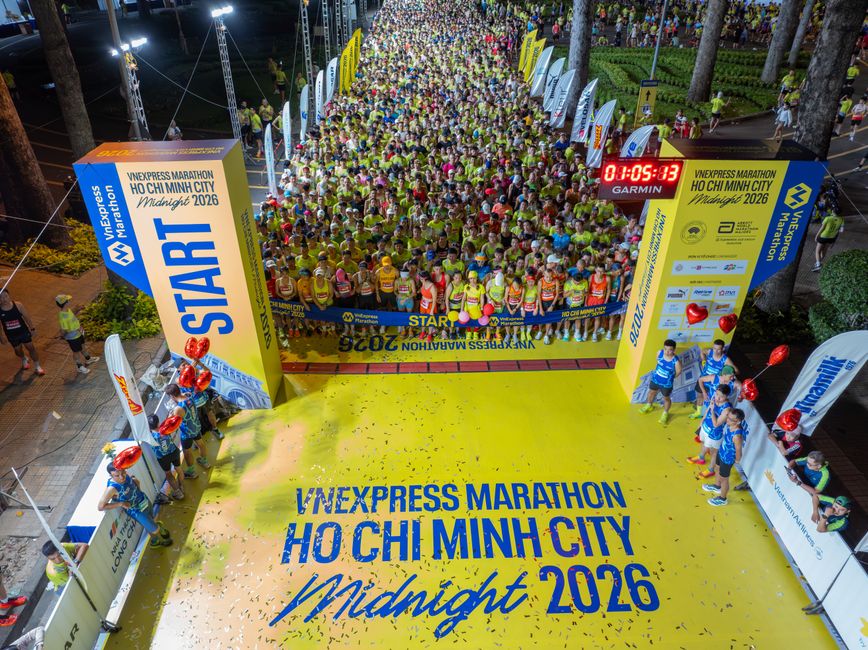 Início de maratona noturna com dezenas de corredores alinhados na largada, em um evento de corrida em Ho Chi Minh City.