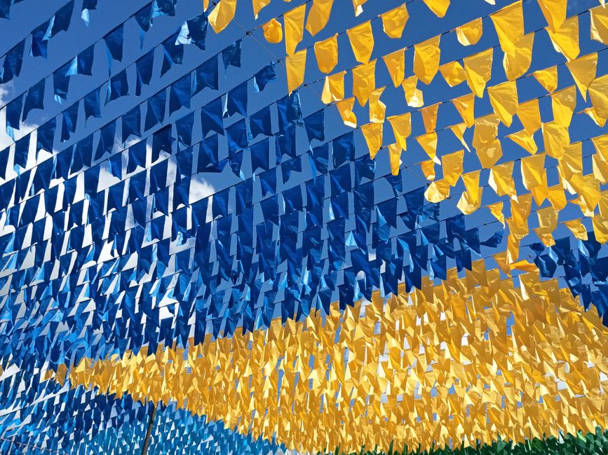 Bandeirinhas decorativas em cores azul e amarelo formando um teto festivo.