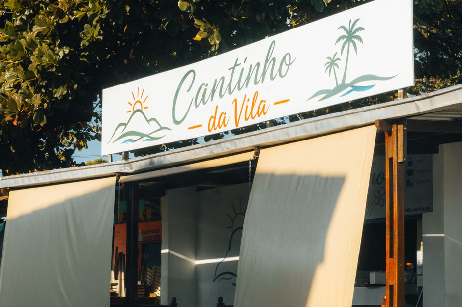 Foto do letreiro de um estabelecimento chamado 'Cantinho da Vila', com elementos que remetem ao contexto de turismo ou lazer na praia ou região turística.