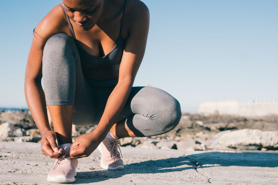 Mulher se preparando para correr ao ar livre, refletindo dedicação à rotina de exercícios físicos.