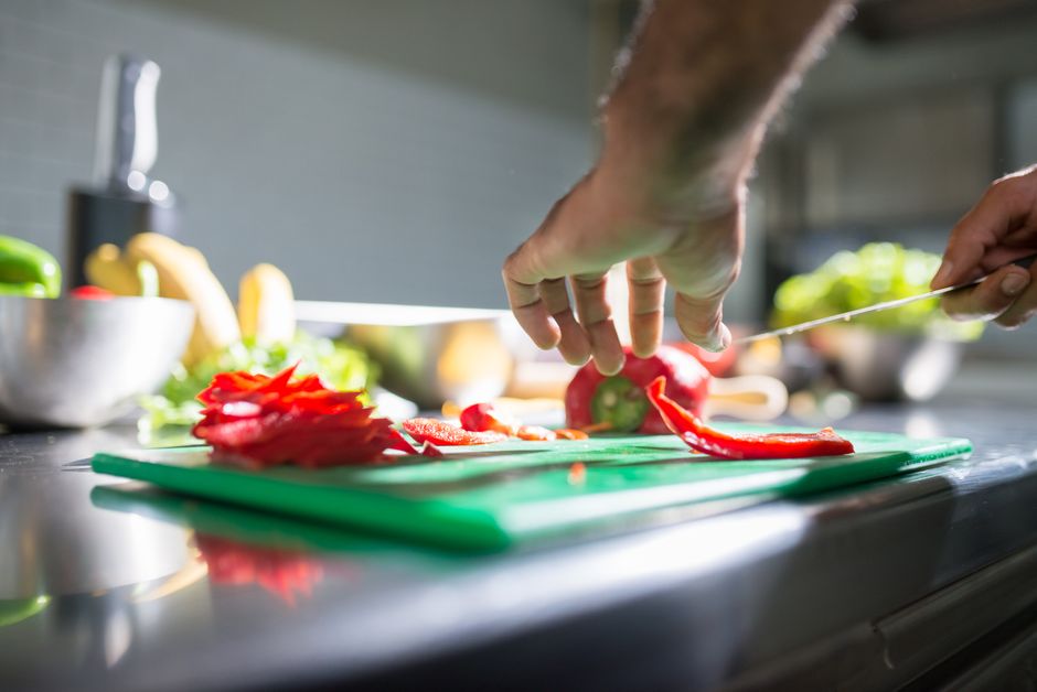 Pessoa preparando ingredientes frescos em uma cozinha moderna, destacando o ato de cozinhar saudável.