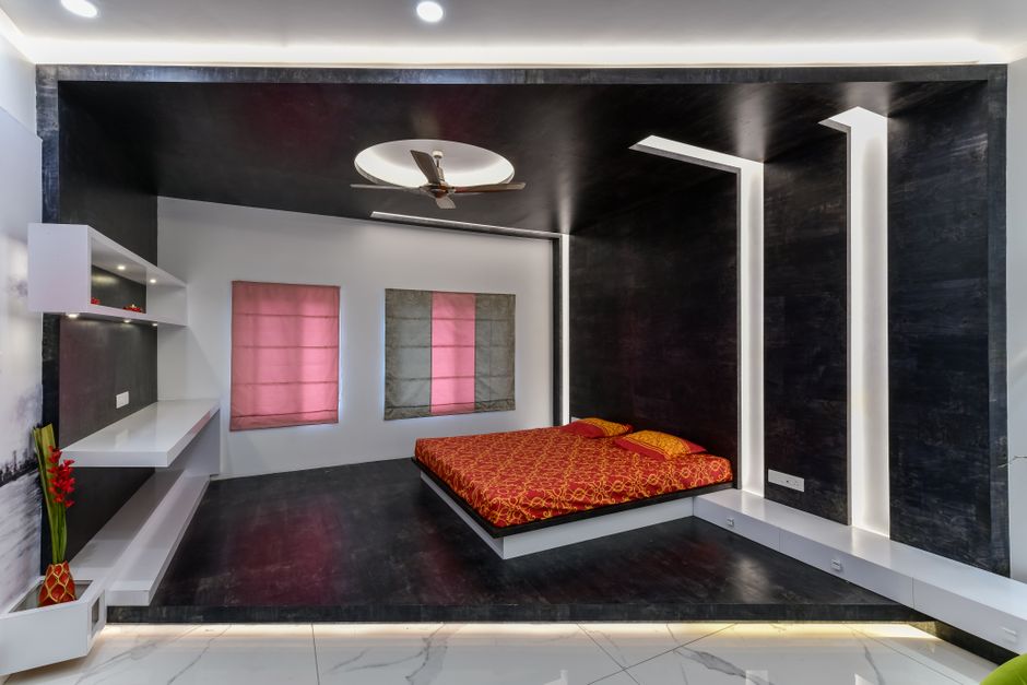 Quarto moderno com decoração minimalista, destaque para a cama com roupa de cama vermelha e iluminação indireta no teto e nas paredes.
