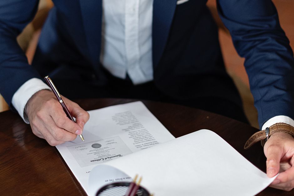 Homem de terno assinando um documento importante, simbolizando negócios ou fechamento de contrato.