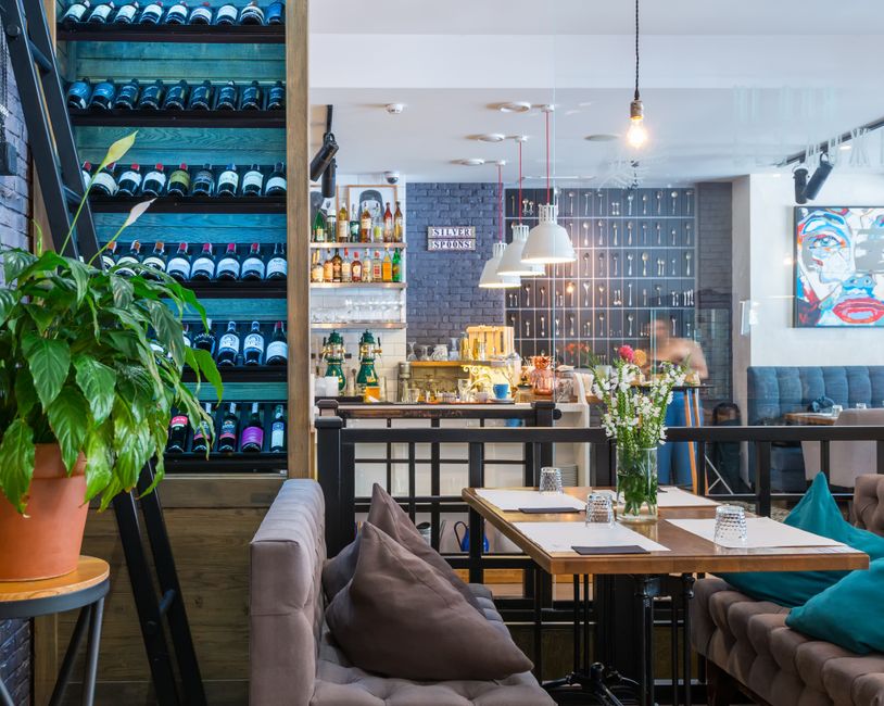 Imagem de um ambiente de restaurante ou café moderno, com decoração aconchegante, plantas e elementos de design contemporâneo, ideal para artigos sobre gastronomia, ambientes de lazer ou planejamento de espaços comerciais.