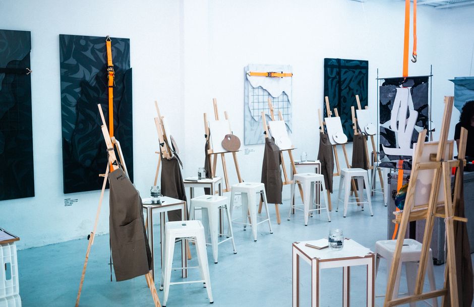 Espaço de aula de pintura ou desenho com cabedorrões e suportes para telas, preparado para um curso artístico.