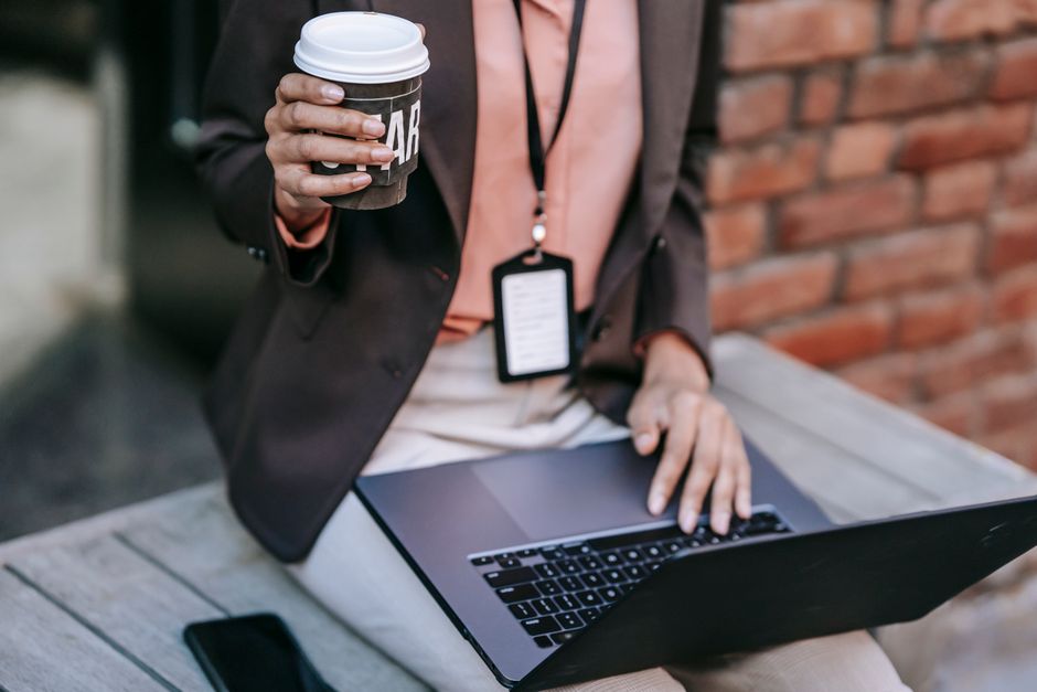 Pessoa em ambiente externo utilizando laptop e smartphone para trabalho ou análise de dados.