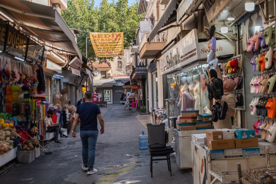Imagem de uma rua de mercado ao ar livre com lojas de artesanato e roupas, representando o comércio local e o empreendedorismo.
