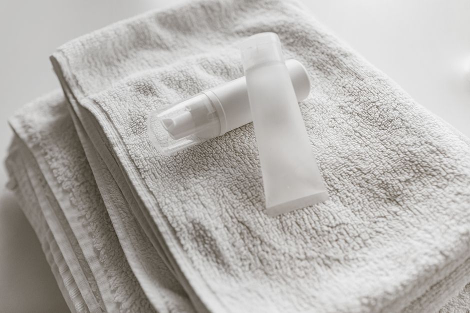 Produtos de higiene pessoal dispostos sobre uma toalha branca, com foco na rotina de cuidados e limpeza diária.
