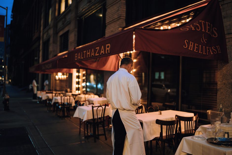 Imagem de um restaurante sofisticado à noite com mesas cuidadosamente arrumadas e um garçom de costas, criando uma atmosfera elegante e acolhedora.