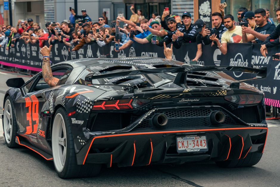 Carro esportivo de alta performance em um evento automobilístico, cercado por torcedores e fãs tirando fotos e comemorando.