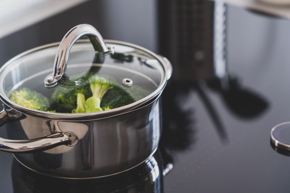 Imagem de uma panela de aço inoxidável com brócolis fervendo, representando culinária saudável e preparo de alimentos naturais.