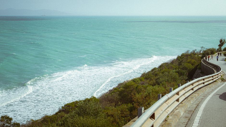 Caminho à beira-mar com vista para o oceano, ideal para temas de turismo, viagens ou relaxamento na natureza.