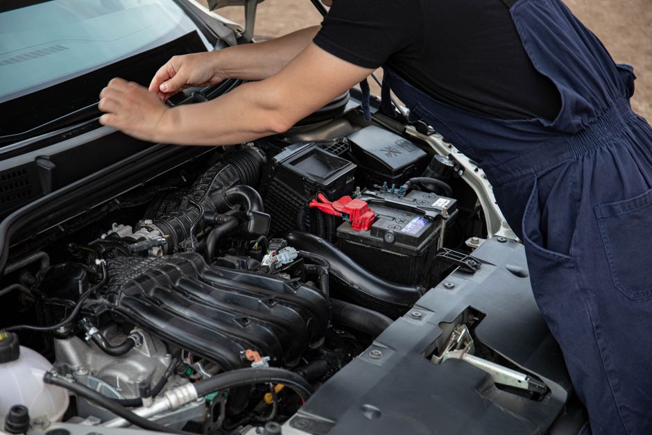 Pessoa realizando manutenção em um motor de carro, focada na inspeção e cuidado com o veículo.