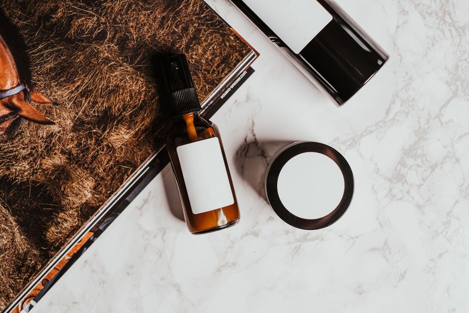 Imagem de produtos de cuidados pessoais e bens de beleza dispostos sobre uma superfície de mármore, sugerindo um ambiente de rotina de autocuidado e bem-estar.