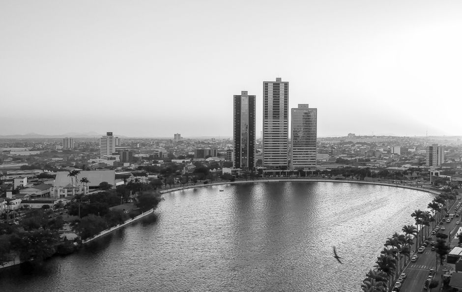 Vista panorâmica de uma cidade com prédios modernos ao lado de um grande corpo de água, transmitindo um ambiente urbano e contemporâneo.