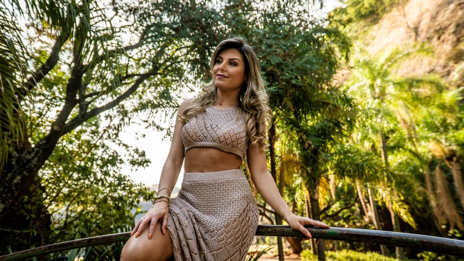 Mulher em ambiente ao ar livre, cercada por natureza, trazendo uma atmosfera de tranquilidade e conexão com o meio ambiente.