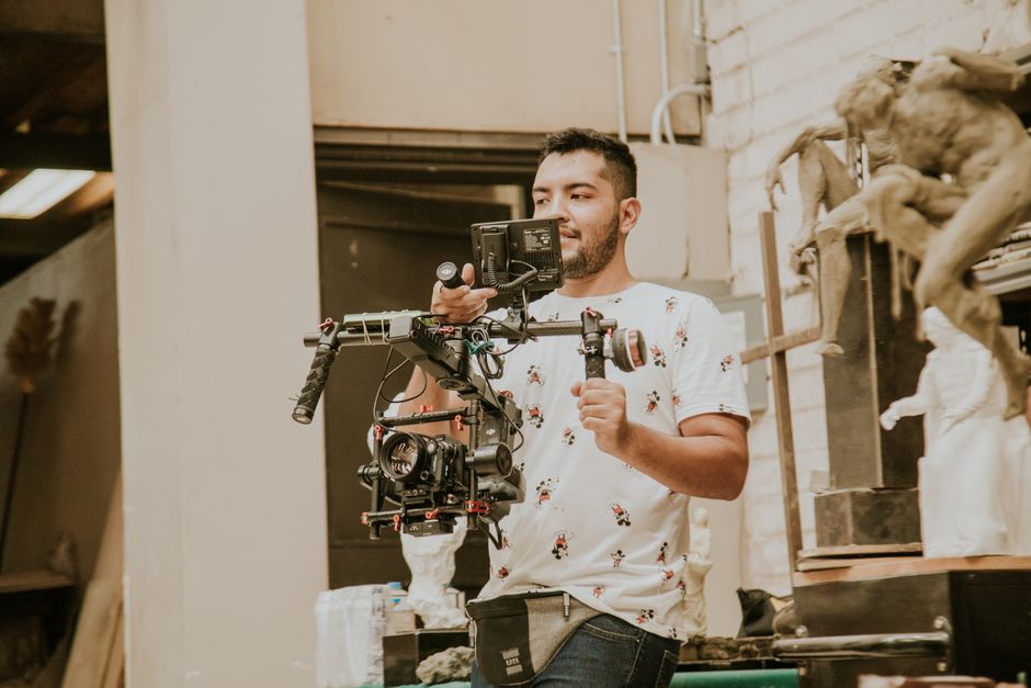 Jovem operador ajustando uma câmera profissional em um ambiente de produção audiovisual. 