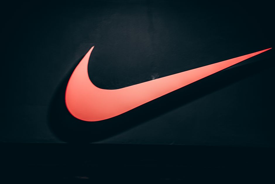 Logotipo da Nike iluminado em fundo escuro, representando esportes e motivação.